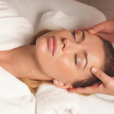 Masażystka wykonuje masaż głowy klientki.